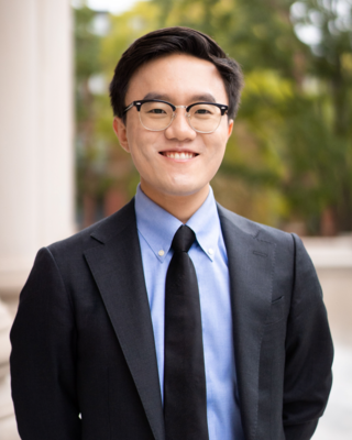 headshot of Brain facing the camera in a dark suit with a light blue shirt