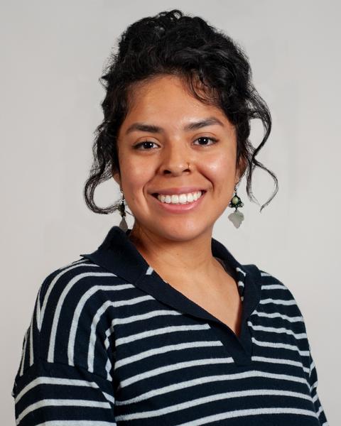 Headshot of Michelle with a gray background wearing a black and white stripped top.