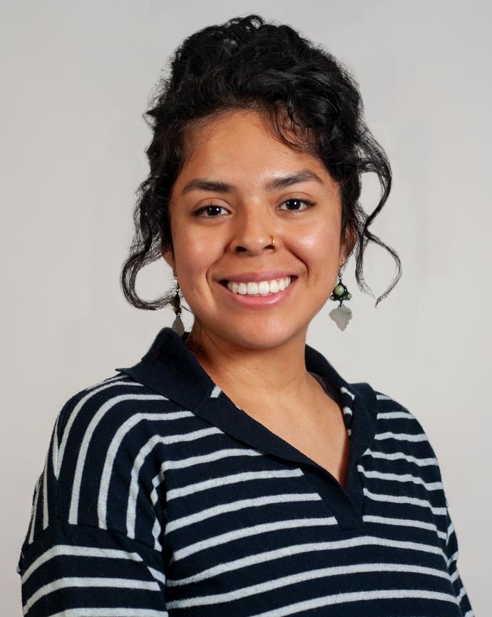 Headshot of Michelle with a gray background wearing a black and white stripped top.