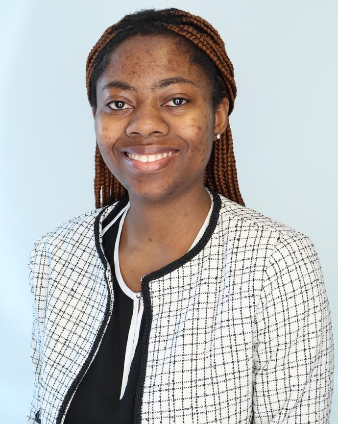 Headshot of Francisca facing the viewer with a blue background wearing a black and white suitjacket